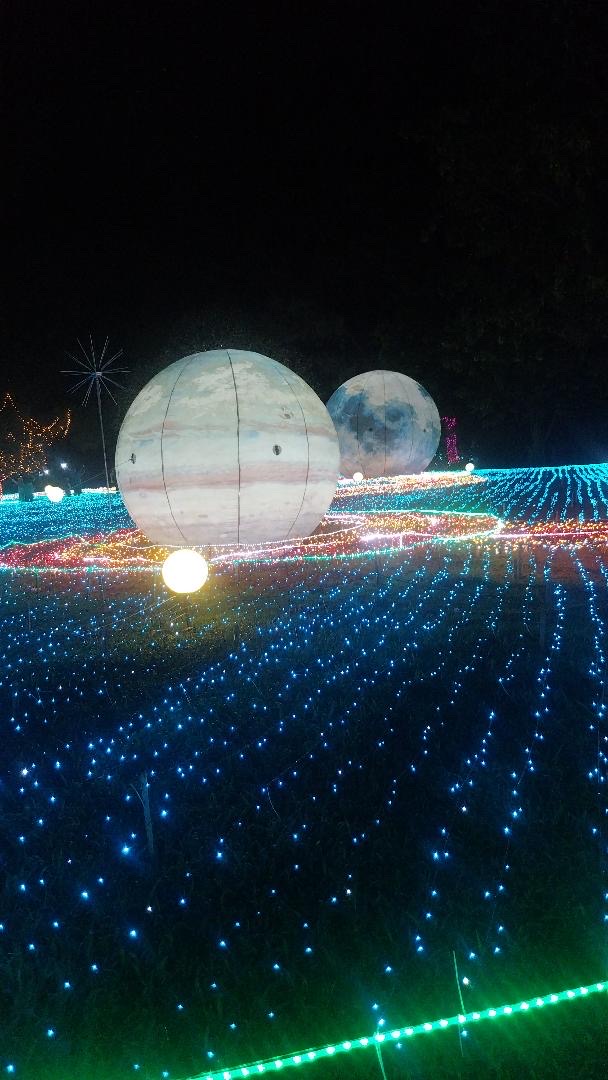 Two illuminated planets, Jupiter and the moon, set on a hill of glittering blue lights.